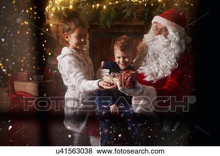 Stock Photo - Young girl and boy receiving gifts from Santa Claus. Fotosearch