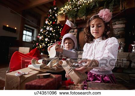 Young girl and boy sorting Christmas gifts, young boy rolling list View Large Photo Image Stock Photograph - Young girl and boy sorting Christmas gifts, young boy rolling list. Fotosearch
