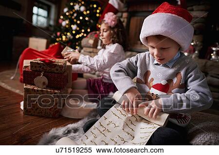 Young girl and boy sorting Christmas gifts, young boy rolling list View Large Photo Image Stock Photography - Young girl and boy sorting Christmas gifts, young boy rolling list. Fotosearch