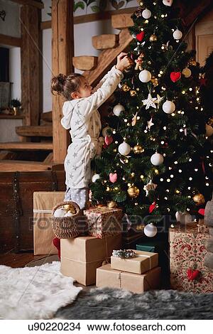 Picture - Young girl decorating Christmas tree. Fotosearch