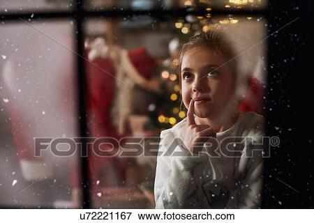 Young girl looking out of window on Christmas eve, Santa in background leaving gifts beside tree View Large Photo Image Stock Photo - Young girl looking out of window on Christmas eve, Santa in background leaving gifts beside tree. Fotosearch