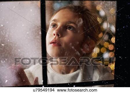 Young girl looking out of window, Christmas tree in background behind her, viewed through window View Large Photo Image Picture - Young girl looking out of window, Christmas tree in background behind her, viewed through window. Fotosearch
