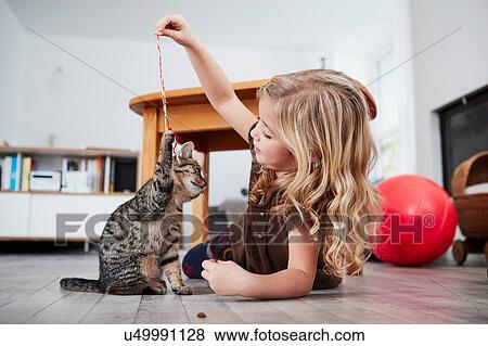 Young girl lying on floor, playing with pet cat View Large Photo Image Stock Photo - Young girl lying on floor, playing with pet cat. Fotosearch