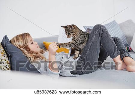 Young girl lying on sofa, playing with pet cat View Large Photo Image Stock Image - Young girl lying on sofa, playing with pet cat. Fotosearch