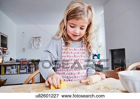 Young girl making cookies, using cookie cutter View Large Photo Image Stock Photo - Young girl making cookies, using cookie cutter. Fotosearch
