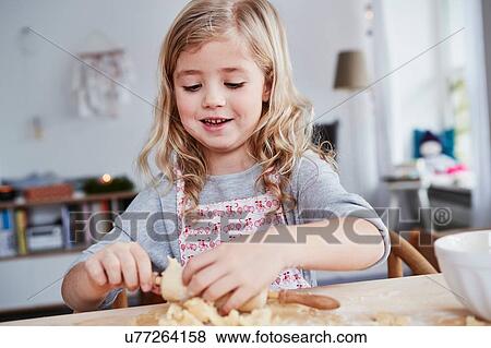 Stock Photo - Young girl rolling out cookie dough, dough stuck to rolling pin. Fotosearch