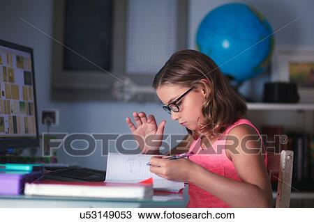 Young girl sitting at desk, doing homework, looking through book View Large Photo Image Stock Image - Young girl sitting at desk, doing homework, looking through book. Fotosearch