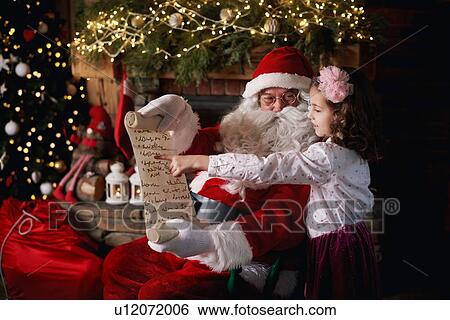 Young girl visiting Santa, pointing to list View Large Photo Image Stock Photograph - Young girl visiting Santa, pointing to list. Fotosearch