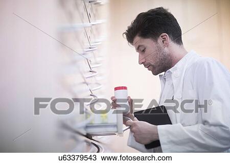 Young male pharmacist removing pill bottle from pharmacy drawer View Large Photo Image Stock Image - Young male pharmacist removing pill bottle from pharmacy drawer. Fotosearch