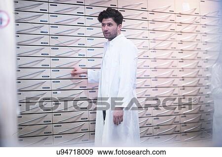 Young male pharmacist standing by pharmacy drawers View Large Photo Image Stock Photo - Young male pharmacist standing by pharmacy drawers. Fotosearch