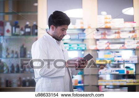 Young male pharmacist using digital tablet in pharmacy View Large Photo Image Picture - Young male pharmacist using digital tablet in pharmacy. Fotosearch