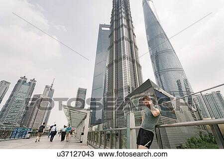 Young male runner leaning against handrail adjusting earphones in Shanghai financial centre, Shanghai, China View Large Photo Image Stock Image - Young male runner leaning against handrail adjusting earphones in Shanghai financial centre, Shanghai, China. Fotosearch