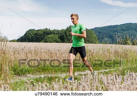 Young male runner running along rural dirt track View Large Photo Image Stock Photograph - Young male runner running along rural dirt track. Fotosearch