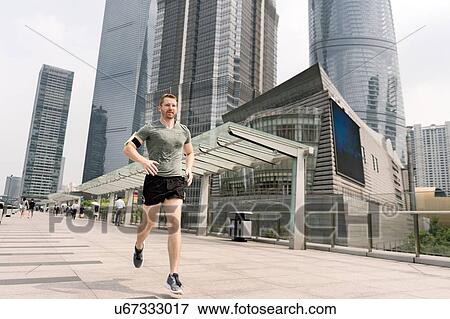 Stock Photo - Young male runner running in Shanghai financial centre, Shanghai, China. Fotosearch