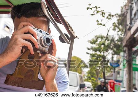 Stock Photograph - Young male tourist in auto rickshaw taking photographs, Bangkok, Thailand. Fotosearch