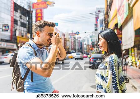Young male tourist photographing girlfriend on street, Bangkok, Thailand View Large Photo Image Stock Photograph - Young male tourist photographing girlfriend on street, Bangkok, Thailand. Fotosearch