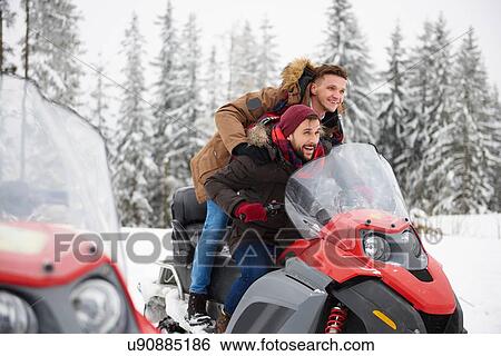 Stock Photograph - Young men riding snowmobile in winter. Fotosearch
