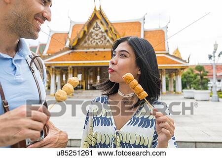 Young tourist couple eating skewered street food outside temple, Bangkok, Thailand View Large Photo Image Stock Image - Young tourist couple eating skewered street food outside temple, Bangkok, Thailand. Fotosearch