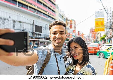Young tourist couple taking smartphone selfie on street, Bangkok, Thailand View Large Photo Image Stock Image - Young tourist couple taking smartphone selfie on street, Bangkok, Thailand. Fotosearch