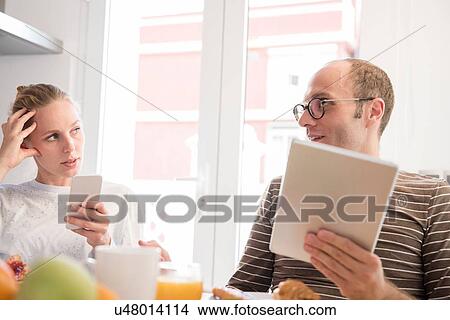 Young woman and boyfriend holding smartphone and digital tablet at table View Large Photo Image Picture - Young woman and boyfriend holding smartphone and digital tablet at table. Fotosearch