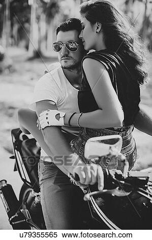 Stock Photography - Young woman astride boyfriend on motorcycle, Krabi, Thailand, B&W. Fotosearch