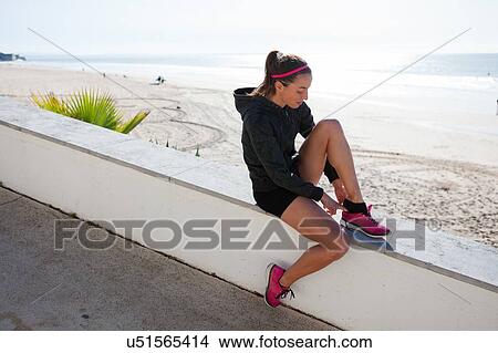 Young woman at beach putting on training shoe, Carcavelos, Lisboa, Portugal, Europe View Large Photo Image Picture - Young woman at beach putting on training shoe, Carcavelos, Lisboa, Portugal, Europe. Fotosearch