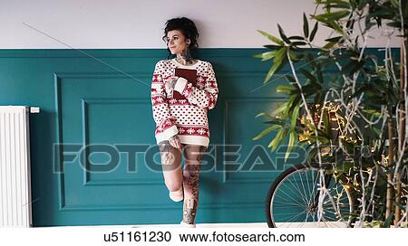 Young woman at home, leaning against wall, wearing christmas jumper, thoughtful expression View Large Photo Image Stock Image - Young woman at home, leaning against wall, wearing christmas jumper, thoughtful expression. Fotosearch