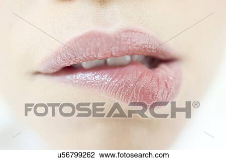 Stock Image - Young woman biting lip, close up.. Fotosearch