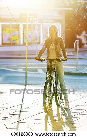 Stock Photo - Young woman cycling in European city.. Fotosearch