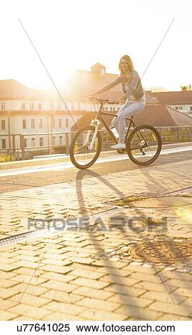 Stock Photography - Young woman cycling in European city.. Fotosearch