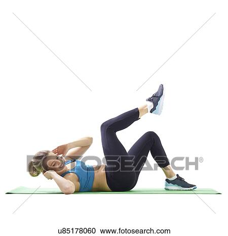 Stock Image - Young woman doing lateral crunch, side view.. Fotosearch
