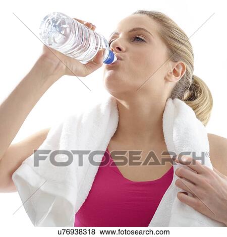 Stock Photo - Young woman drinking from water bottle, studio shot.. Fotosearch