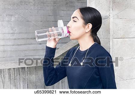 Stock Image - Young woman drinking water from bottle.. Fotosearch