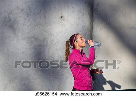 Picture - Young woman drinking water from water bottle. Fotosearch
