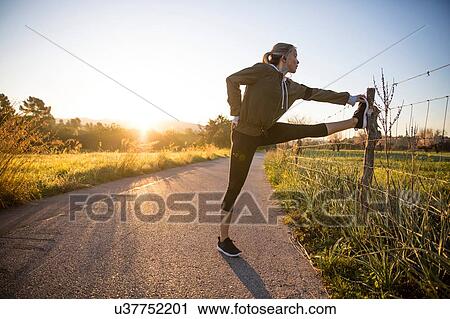Young woman exercising in rural setting, stretching leg View Large Photo Image Stock Image - Young woman exercising in rural setting, stretching leg. Fotosearch
