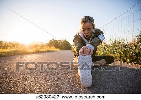 Young woman exercising in rural setting, stretching leg View Large Photo Image Stock Photo - Young woman exercising in rural setting, stretching leg. Fotosearch