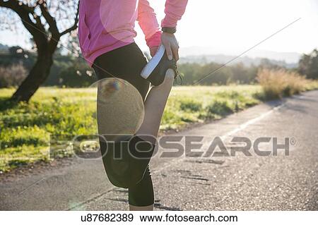 Young woman exercising in rural setting, stretching leg, low section View Large Photo Image Stock Photo - Young woman exercising in rural setting, stretching leg, low section. Fotosearch
