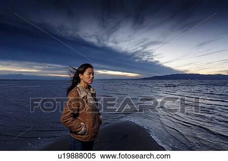 Stock Photography - Young woman gazing on windy beach at dusk, Tarragona, Catalonia, Spain. Fotosearch