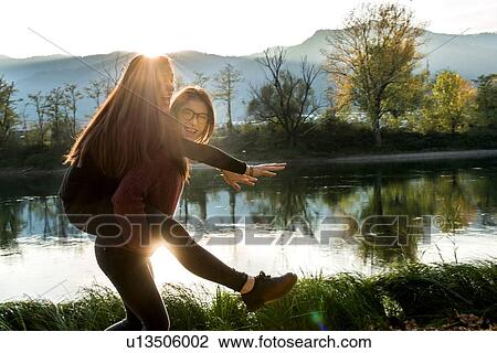 Young woman giving best friend piggy back on riverbank, Calolziocorte, Lombardy, Italy View Large Photo Image Stock Image - Young woman giving best friend piggy back on riverbank, Calolziocorte, Lombardy, Italy. Fotosearch