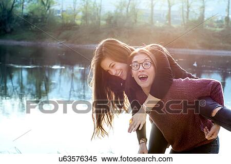 Young woman giving best friend piggy back by river, Calolziocorte, Lombardy, Italy View Large Photo Image Stock Photography - Young woman giving best friend piggy back by river, Calolziocorte, Lombardy, Italy. Fotosearch