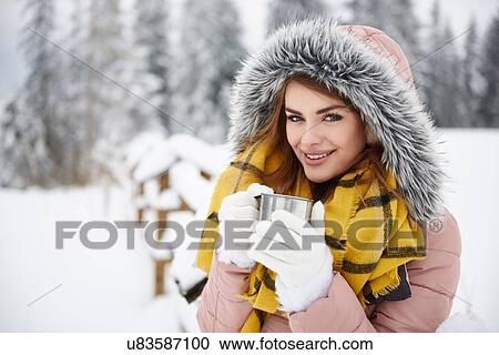 Stock Image - Young woman having coffee outdoors in winter. Fotosearch