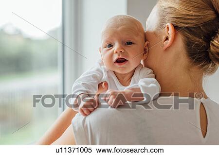 Stock Photography - Young woman holding baby daughter, over shoulder portrait. Fotosearch