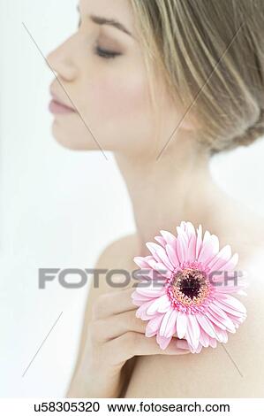 Stock Image - Young woman holding flower, portrait.. Fotosearch