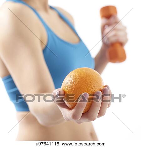 Young woman holding orange and hand weight, studio shot. View Large Photo Image Stock Photography - Young woman holding orange and hand weight, studio shot.. Fotosearch