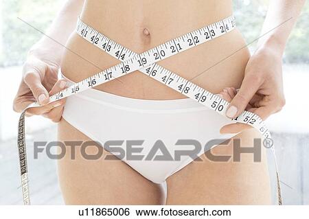 Young woman holding tape measure around her waist. View Large Photo Image Stock Photograph - Young woman holding tape measure around her waist.. Fotosearch