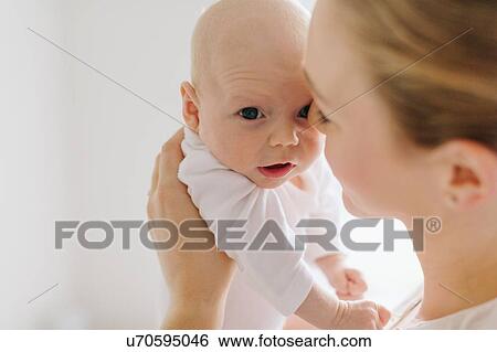 Stock Photograph - Young woman holding up baby daughter, cropped. Fotosearch