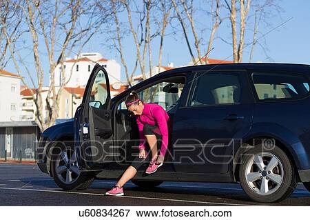 Young woman in car tying shoelace on training shoe, stretching legs View Large Photo Image Stock Photo - Young woman in car tying shoelace on training shoe, stretching legs. Fotosearch