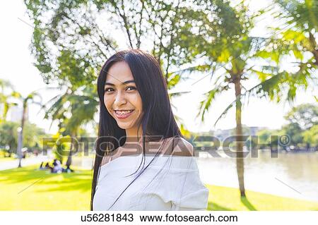 Stock Image - Young woman in park, Bangkok, Thailand. Fotosearch
