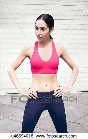 Stock Photo - Young woman in pink sports bra with hands on hips.. Fotosearch