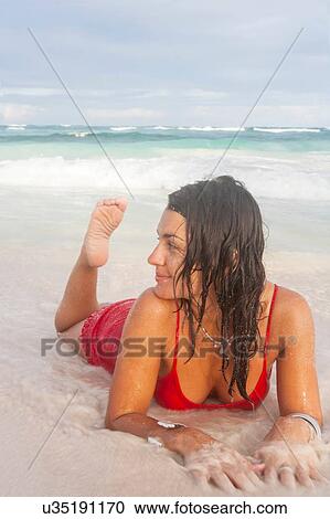 Young woman in red swimming costume lying on beach at water's edge, Tulum, Quintana Roo, Mexico View Large Photo Image Stock Image - Young woman in red swimming costume lying on beach at water's edge, Tulum, Quintana Roo, Mexico. Fotosearch